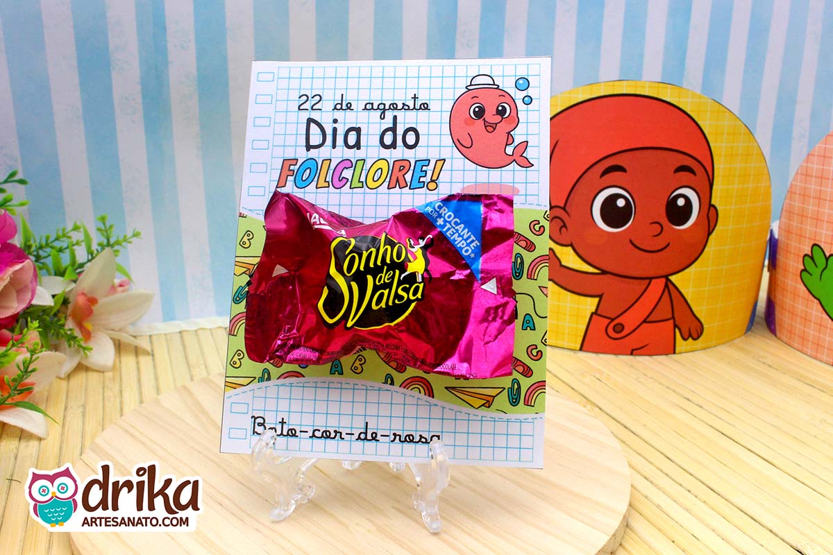 Cartão porta-bombom do Boto-cor-de-rosa com bombom Sonho de Valsa em suporte transparente sobre madeira