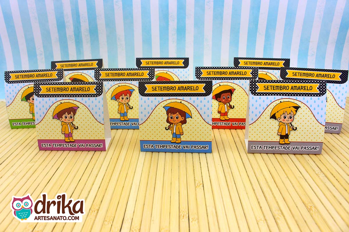 Vários porta-bombons do Setembro Amarelo com personagens diversos enfileirados em fundo de madeira clara