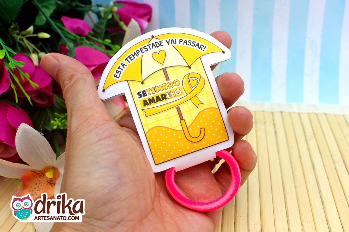 Porta-xuxinha guarda-chuva amarelo do Setembro Amarelo com frase e xuxinha rosa na mão.