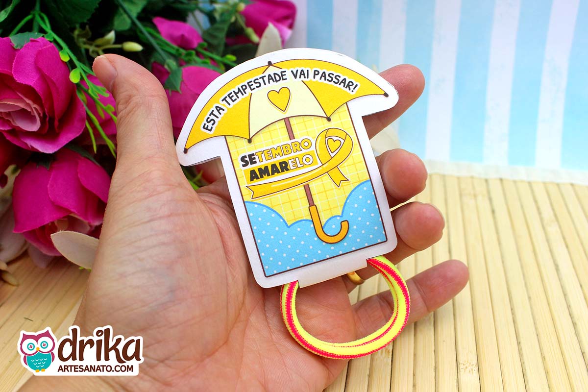 Porta-xuxinha guarda-chuva amarelo e azul do Setembro Amarelo com xuxinha amarela e vermelha na mão.