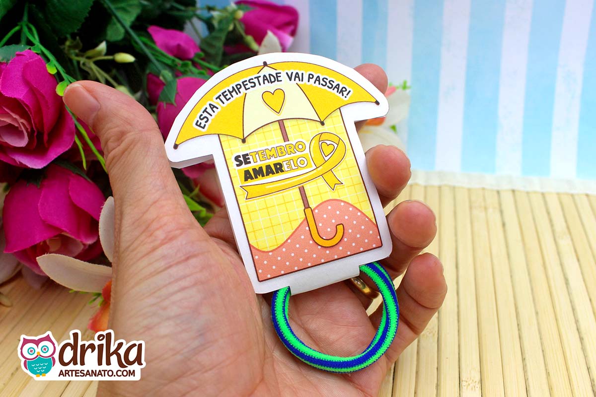 Porta-xuxinha guarda-chuva amarelo e vermelho do Setembro Amarelo com xuxinha azul e verde na mão.