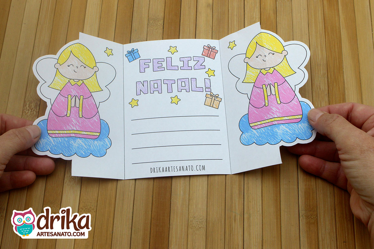 Cartão de Natal aberto com anjinhas, "Feliz Natal", presentes e estrelas, com espaço para mensagem.