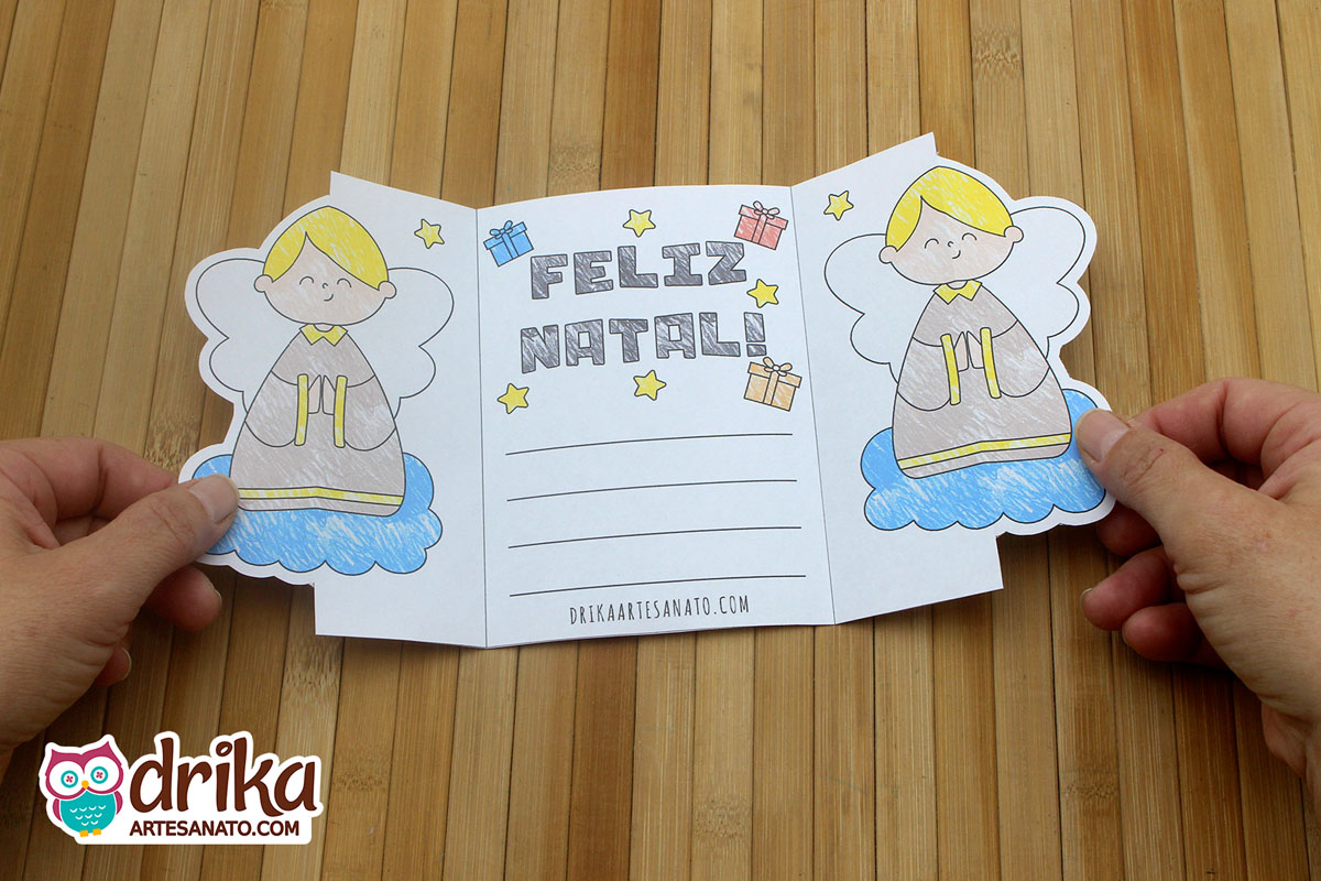Cartão de Natal aberto com anjos, mensagem "Feliz Natal", estrelas, presentes e espaço para mensagem
