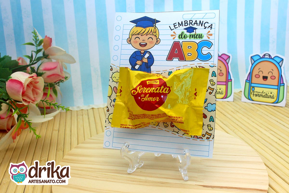 Cartão porta-bombom com menino loiro de beca azul, segurando diploma, com bombom Serenata de Amor.