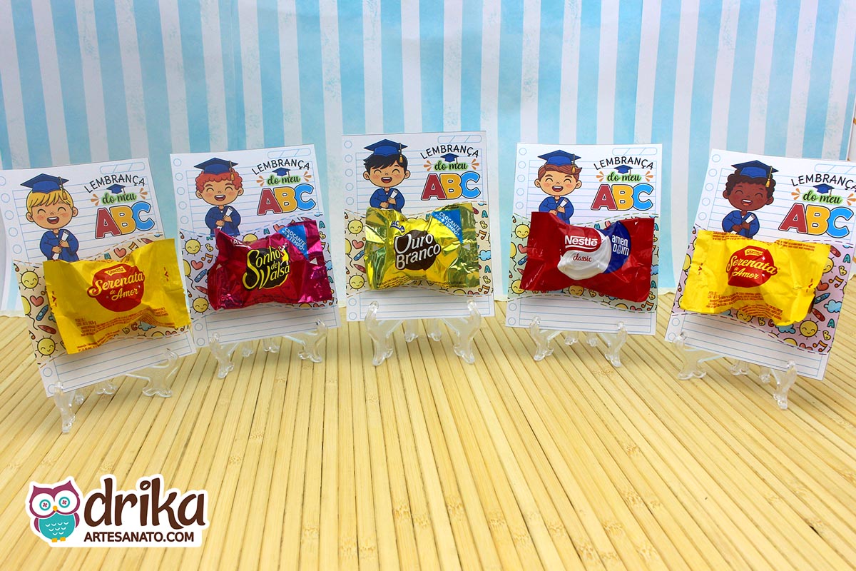 Cinco cartões porta-bombom de formatura ABC para meninos, cada um com um personagem diferente e bombons variados em suportes transparentes.