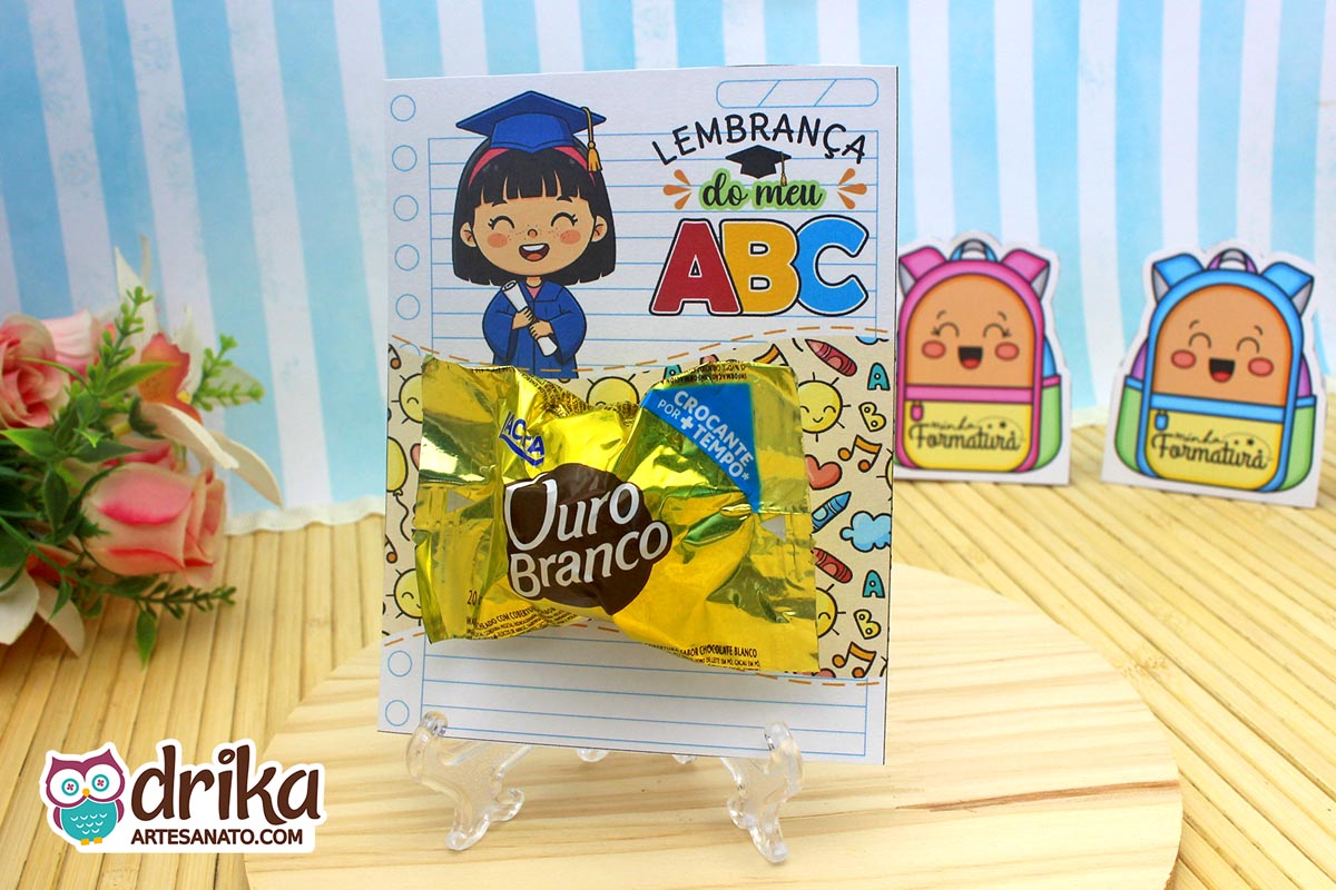 Cartão porta-bombom de formatura ABC com menina de cabelo preto segurando diploma e bombom Ouro Branco em suporte transparente