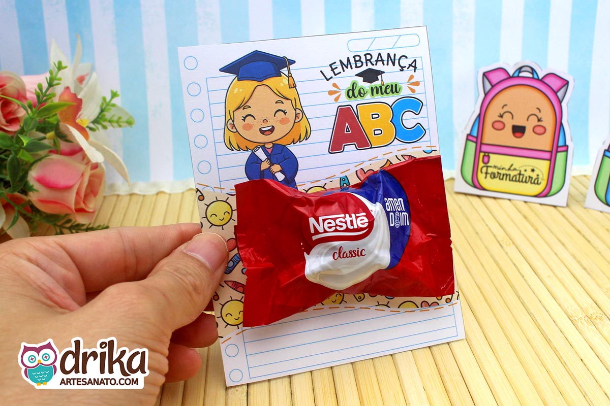 Cartão porta-bombom Formatura ABC com menina loira e bombom Classic sendo segurado por uma mão