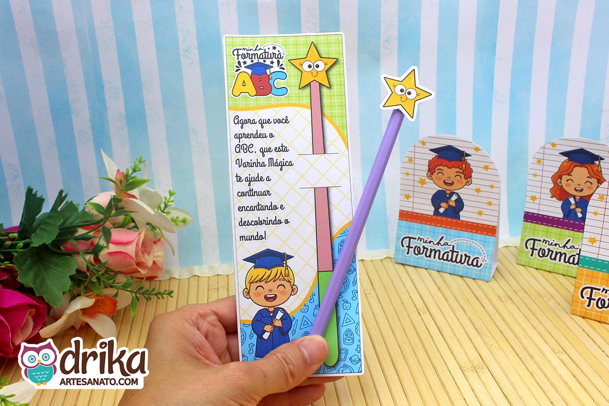 Cartão porta-lápis Formatura ABC com menino loiro segurando diploma e lápis roxo com estrela em mão sobre fundo floral.