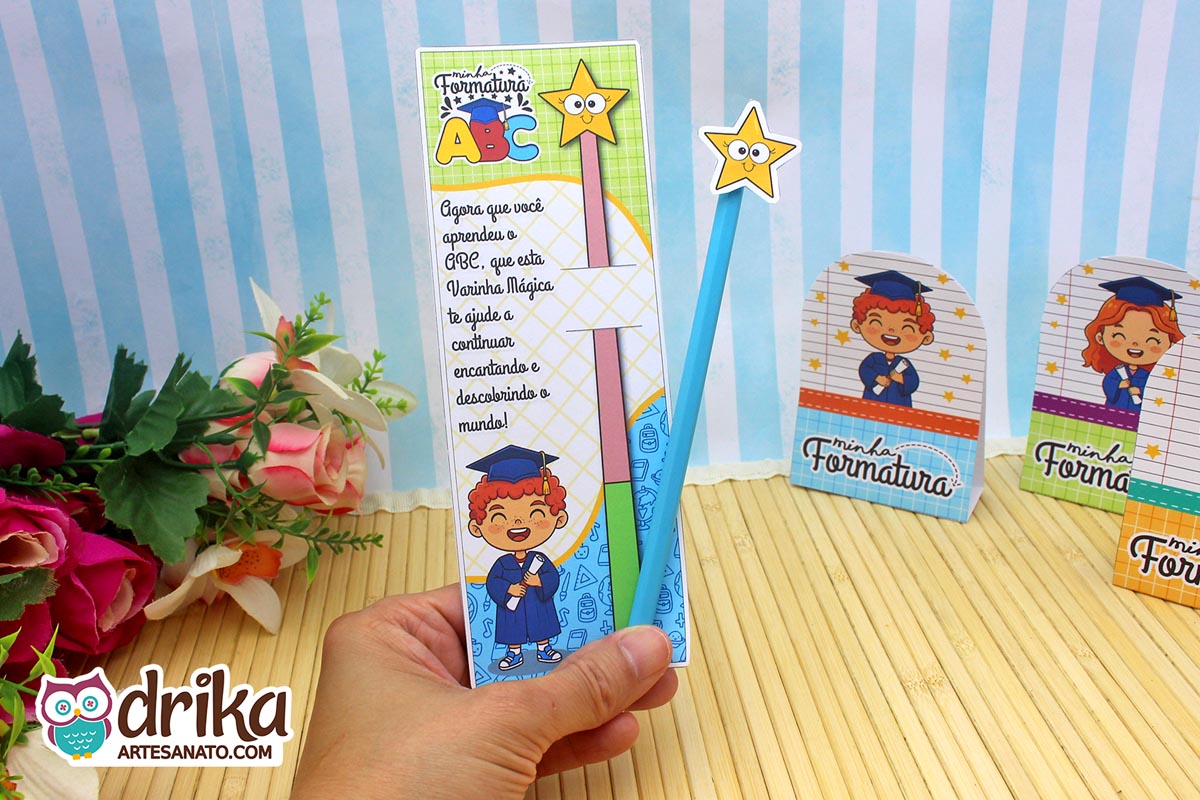 Cartão porta-lápis Formatura ABC com menino ruivo segurando diploma e lápis azul com estrela sobre fundo floral.