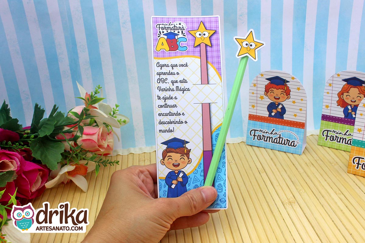 Cartão porta-lápis Formatura ABC com menino de cabelo castanho segurando diploma e lápis verde com estrela sobre fundo floral.