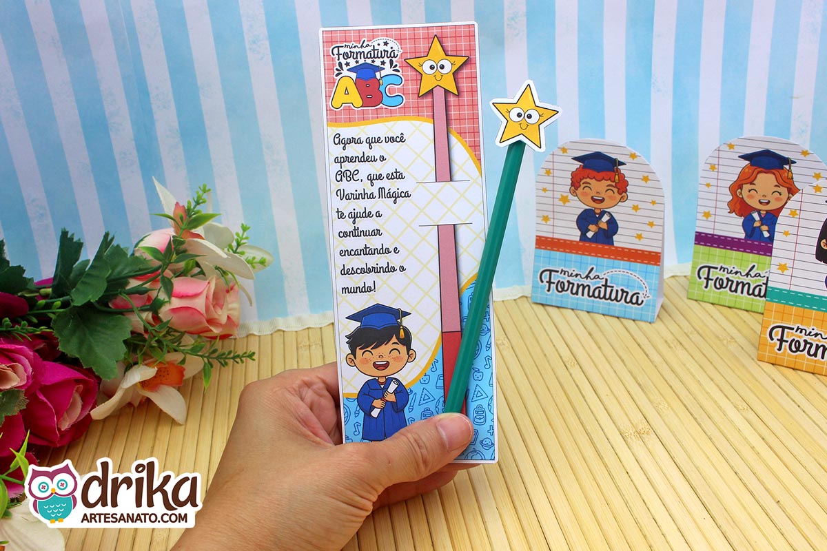 Mão segurando cartão porta-lápis formatura ABC com menino de cabelo preto, lápis verde com estrela amarela e frase inspiradora.