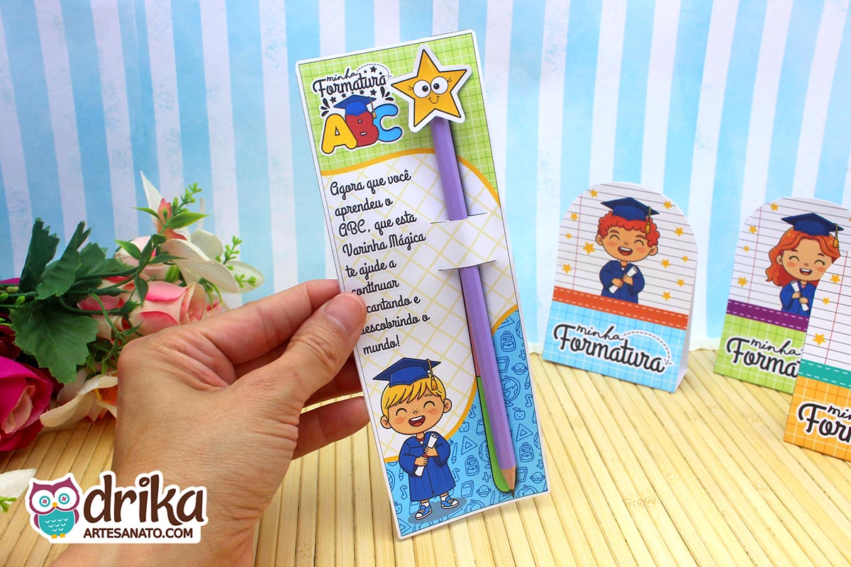 Mão segurando cartão porta-lápis formatura ABC com menino loiro, lápis com estrela e frase inspiradora.
