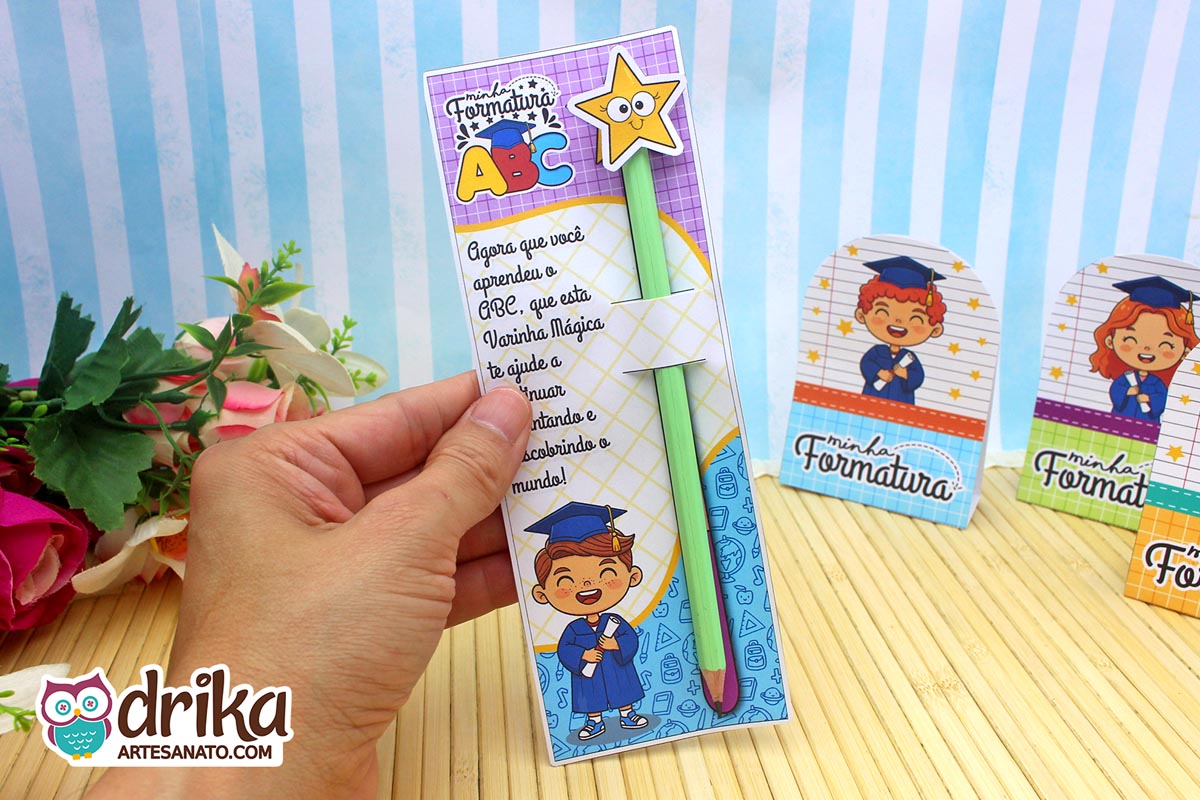 Mão segurando cartão porta-lápis formatura ABC com menino de cabelo castanho, lápis com estrela e mensagem inspiradora.