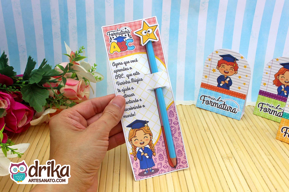 Mão segurando cartão formatura ABC com menina de cabelo castanho, lápis azul com estrela, frase e desenhos.