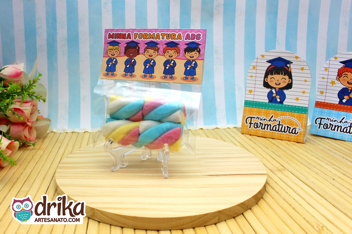 Saquinho transparente com marshmallow colorido fechado com lapela de formatura ABC em tons de rosa e laranja.