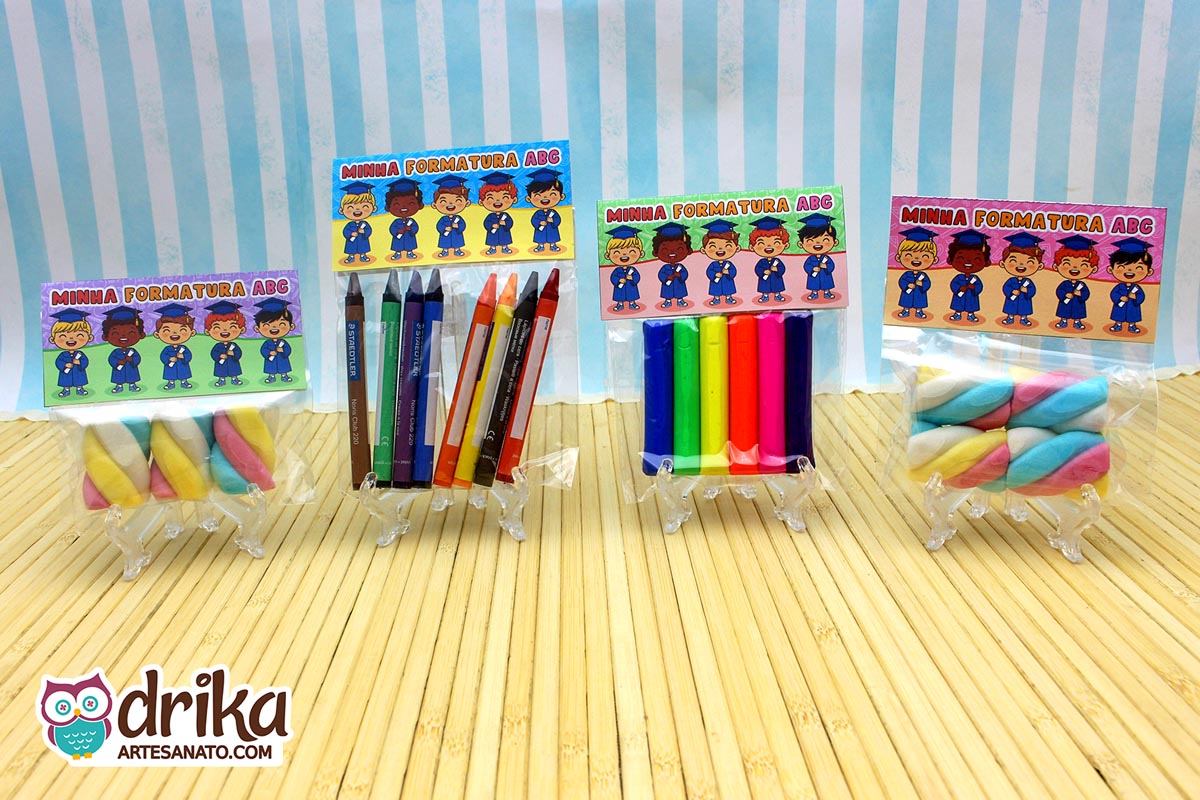 Quatro lembrancinhas de formatura ABC com lapelas de diferentes tons de pele, saquinhos com marshmallow, giz de cera e massinha.