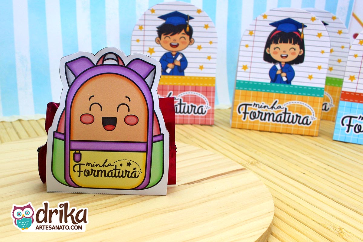 Mochila porta-bombom roxa e laranja com rosto de menino sorrindo, bombom vermelho à mostra e outras lembrancinhas ao fundo