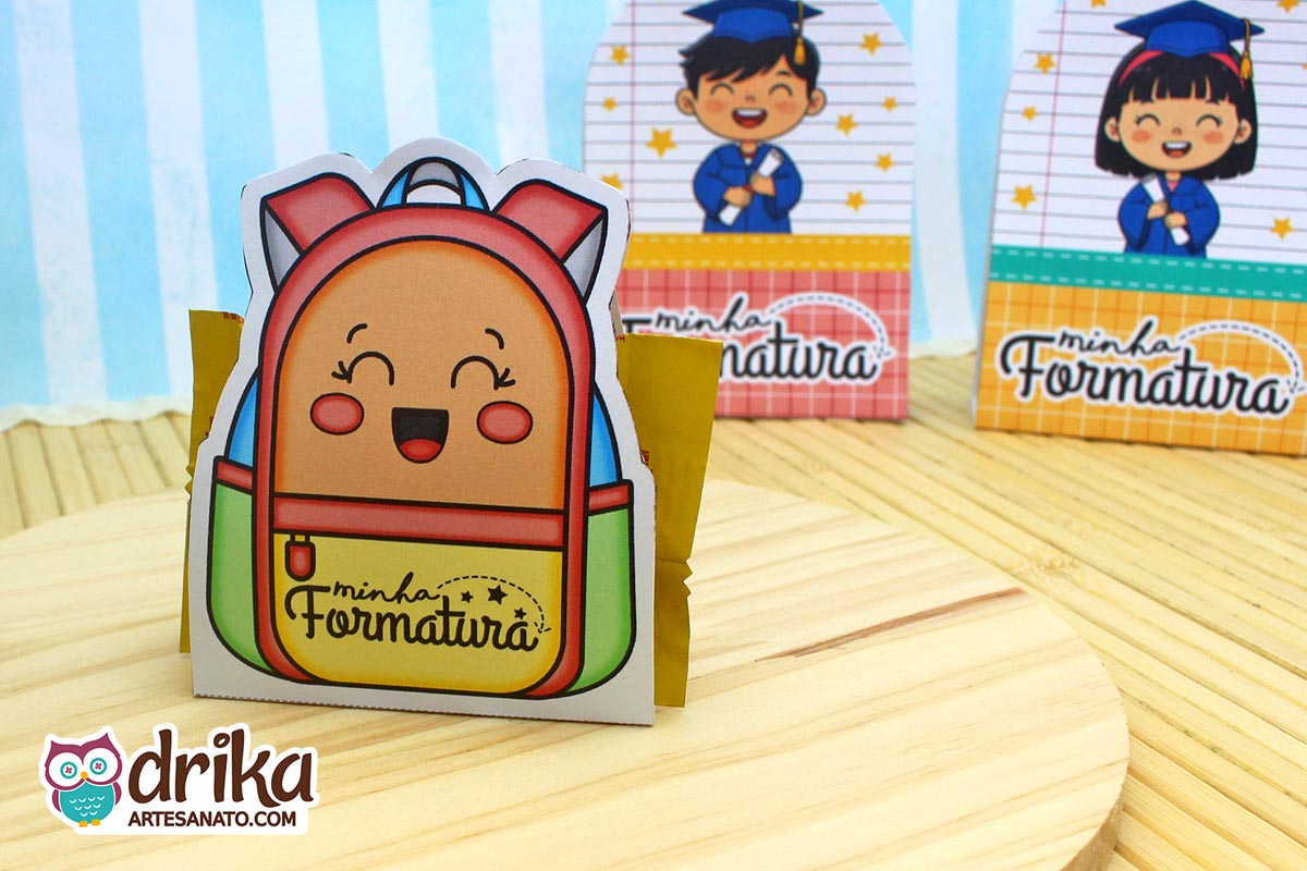 Mochila porta-bombom vermelha e amarela com rosto de menina sorrindo, bombom dourado à mostra e outras lembrancinhas ao fundo