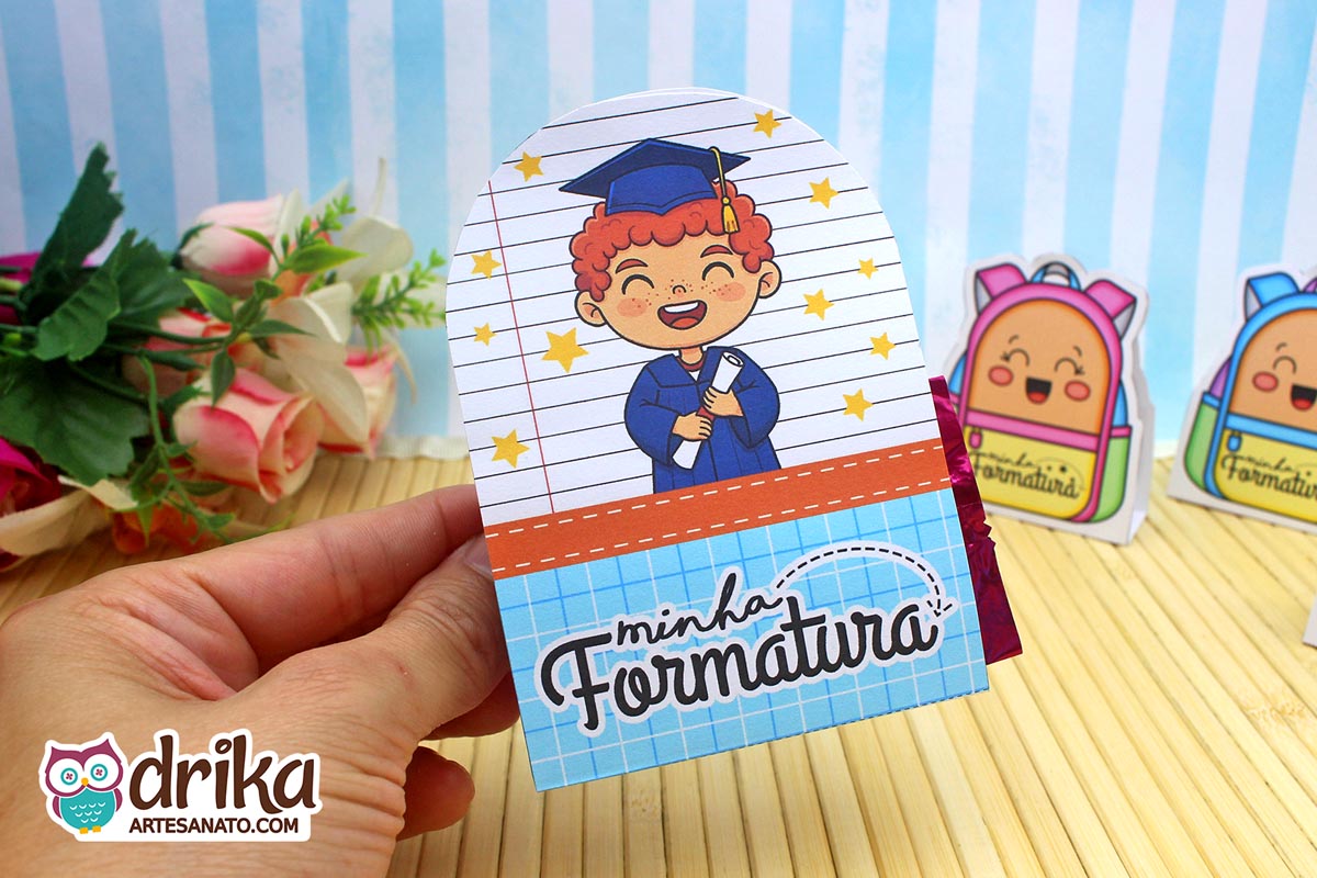 Porta-bombom de formatura ABC com menino ruivo de beca azul segurando diploma, fundo de caderno com estrelas douradas