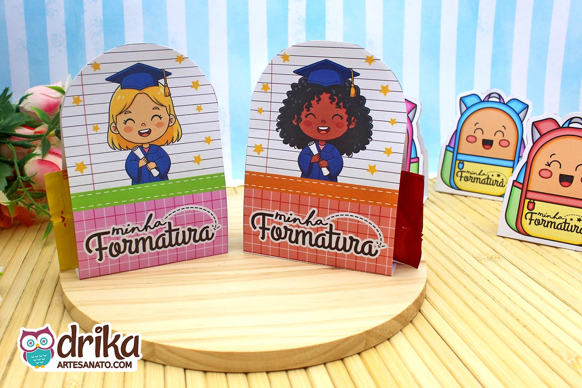 Porta-bombons ABC com meninas de cabelo loiro e crespo, ambas com beca azul e fundo de caderno.
