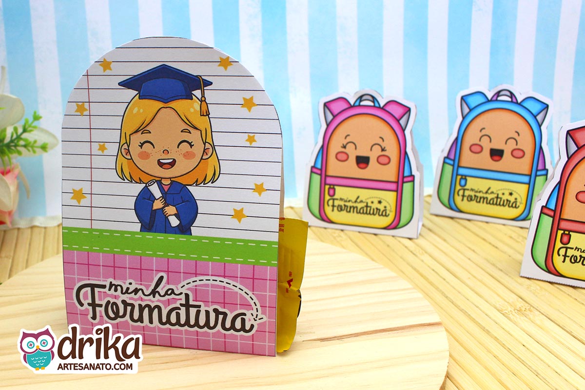 Porta-bombom Formatura ABC com menina loira, beca azul e capelo, segurando diploma em fundo de caderno com estrelas amarelas