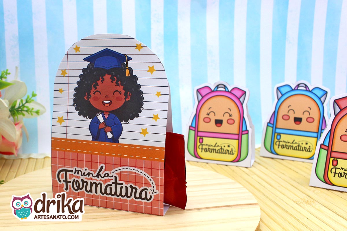 Porta-bombom Formatura ABC com menina de cabelo crespo, beca azul e capelo, segurando diploma em fundo de caderno com estrelas