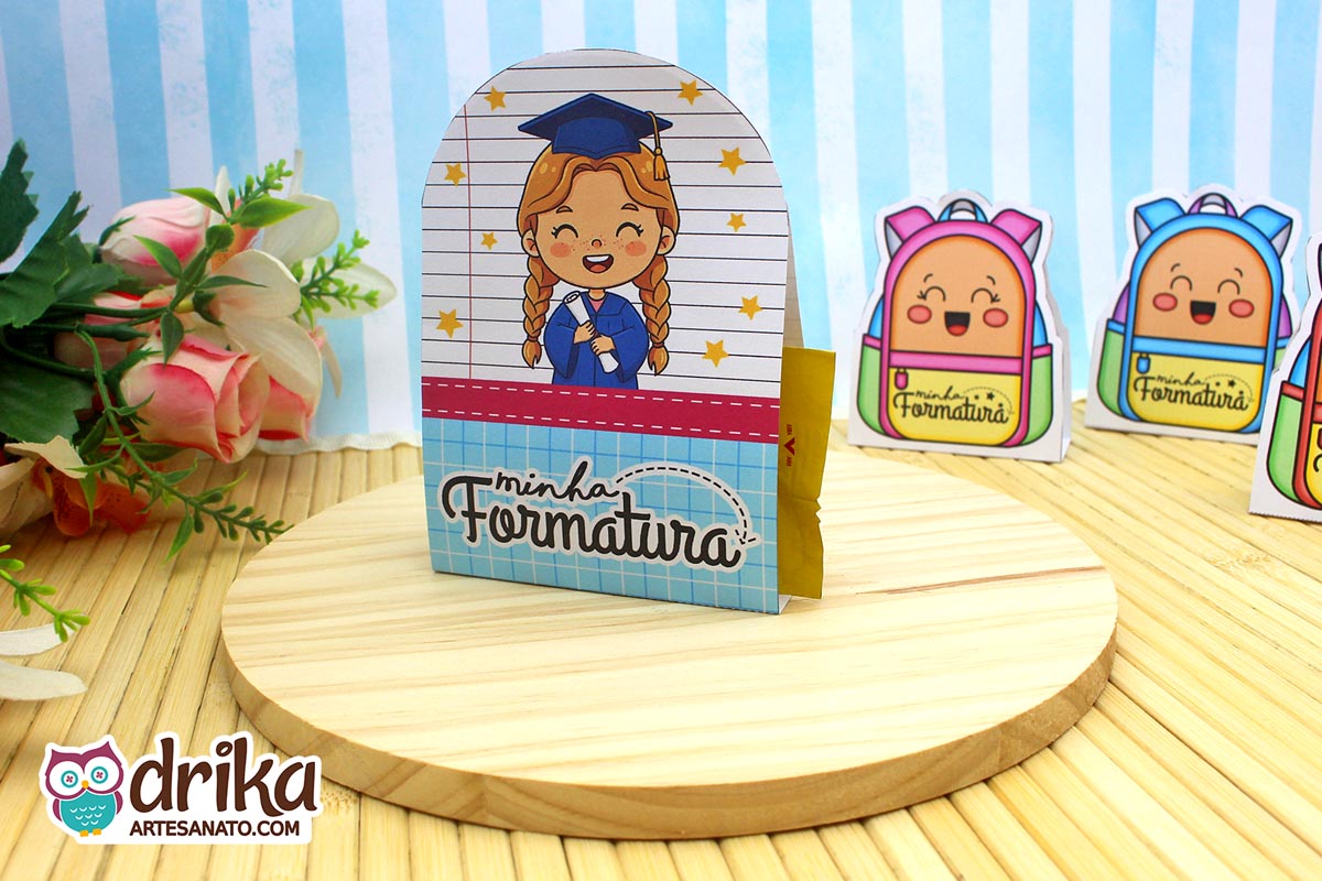 Porta-bombom Formatura ABC com menina de cabelo castanho, beca azul e capelo, segurando diploma em fundo de caderno com estrelas