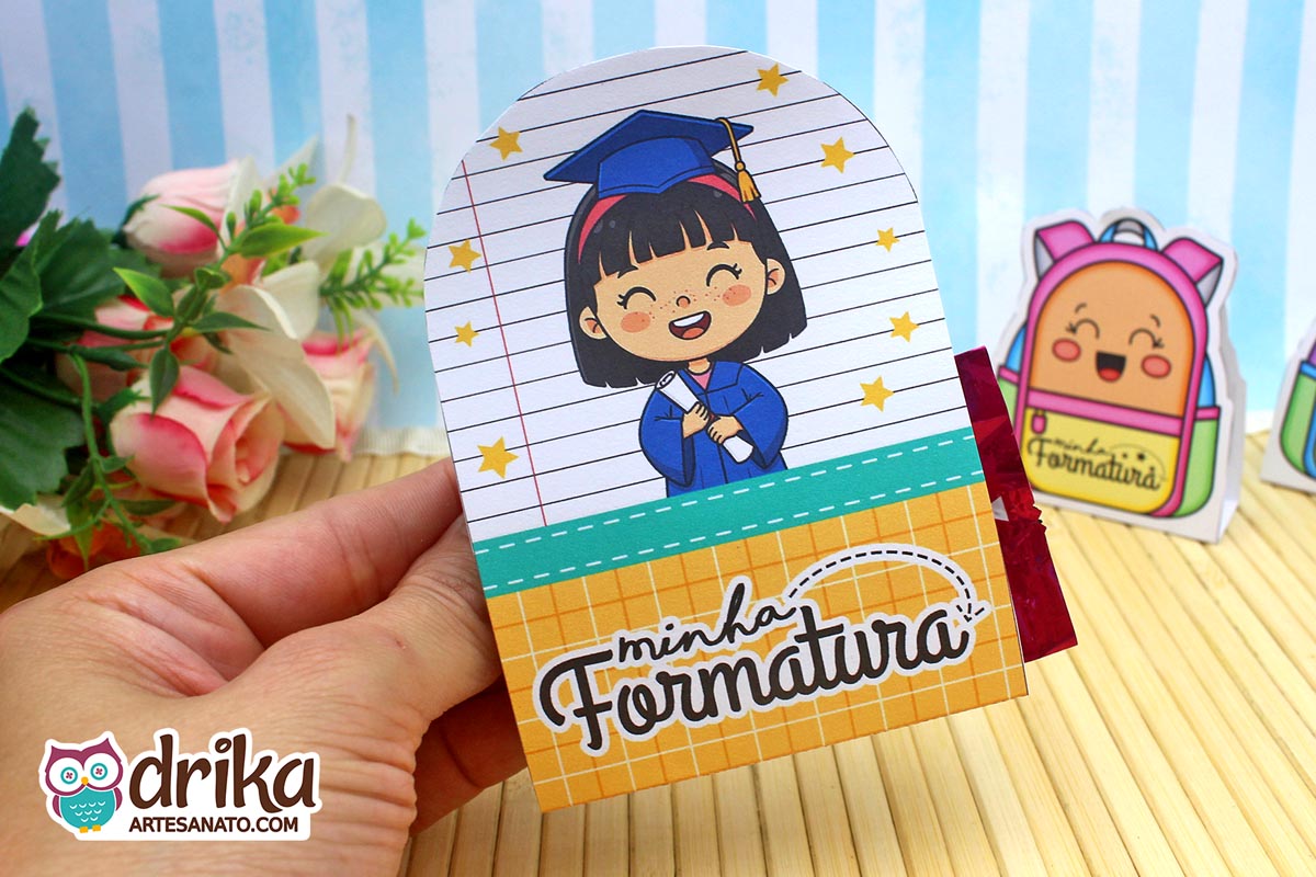 Porta-bombom de formatura com menina de cabelo preto, beca azul e mensagem "Minha Formatura" em fundo mostarda