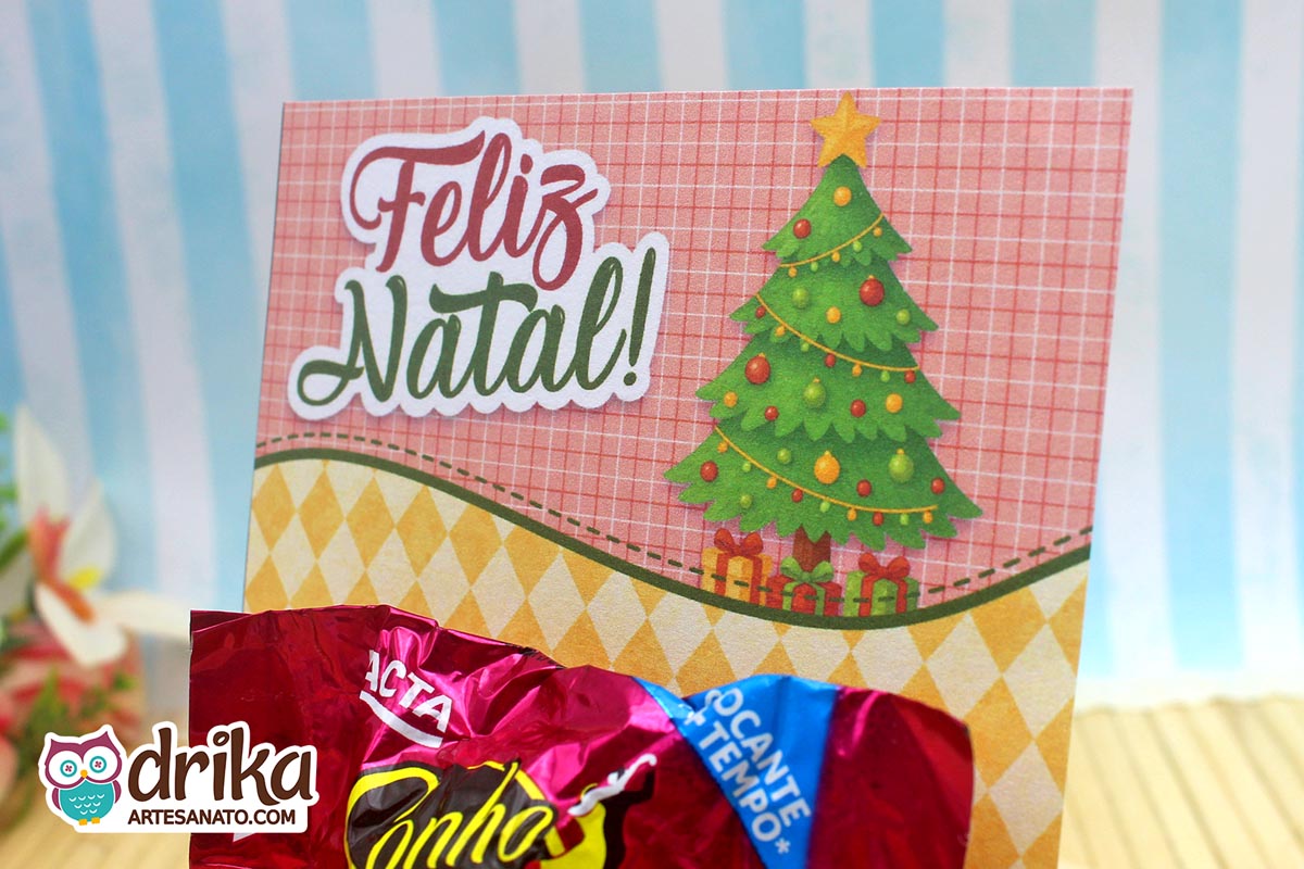 Close-up do cartão porta-bombom de Natal com árvore verde, presentes e bombom Sonho de Valsa.