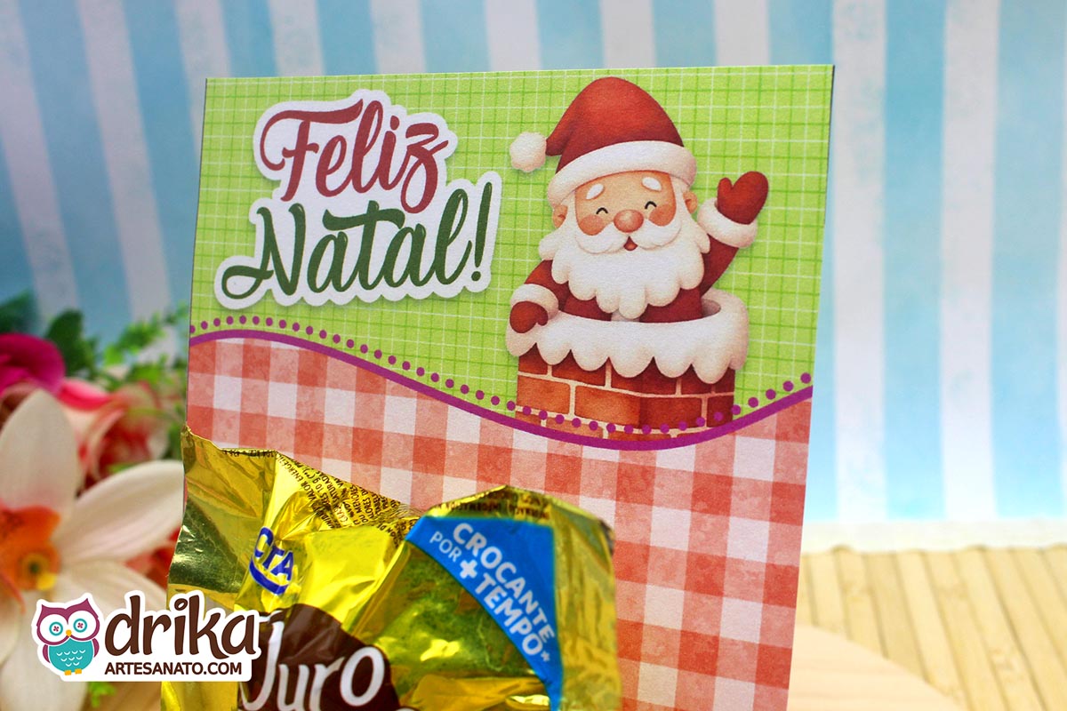 Close do cartão de Natal com Papai Noel na chaminé e bombom Ouro Branco encaixado