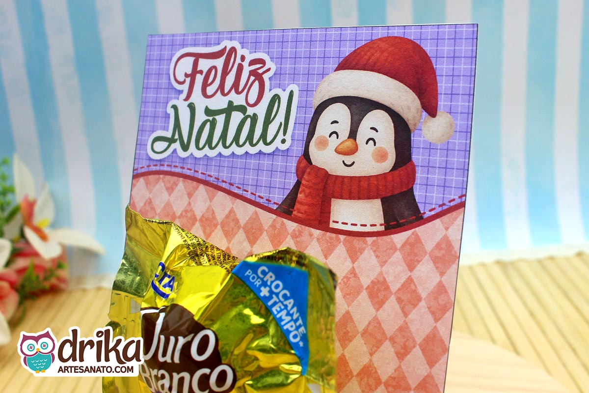Close do cartão porta-bombom de pinguim com bombom Ouro Branco, destacando o design festivo e a mensagem natalina.