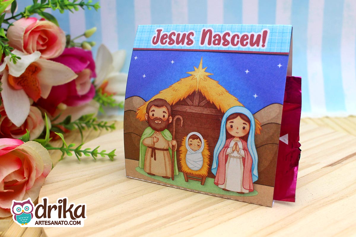 Porta-bombom de Natal com ilustração do presépio e a frase "Jesus Nasceu!" em fundo azul estrelado.
