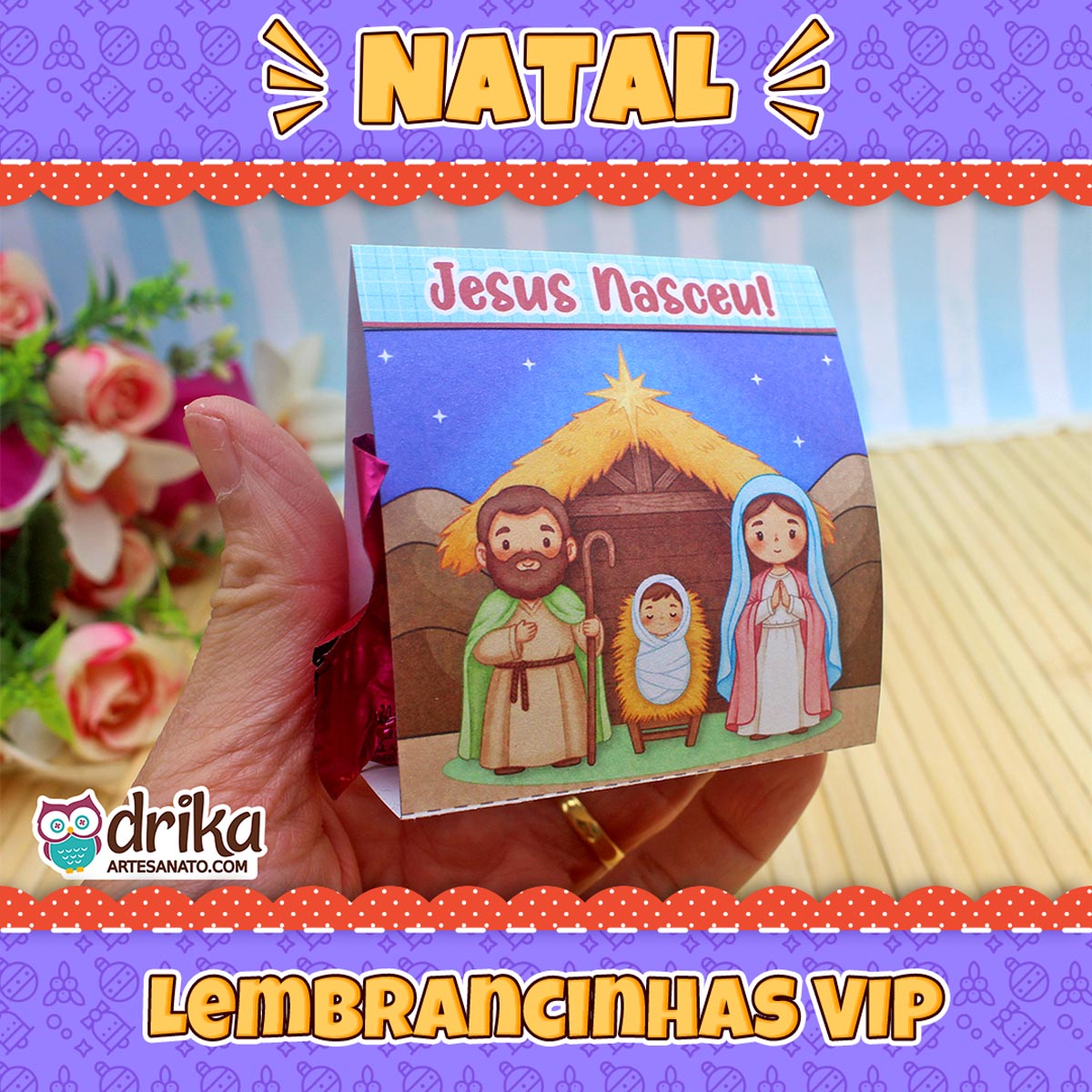 Mão segurando porta-bombom do presépio com bombom rosa, cercado por decoração natalina e texto "Lembrancinhas VIP"