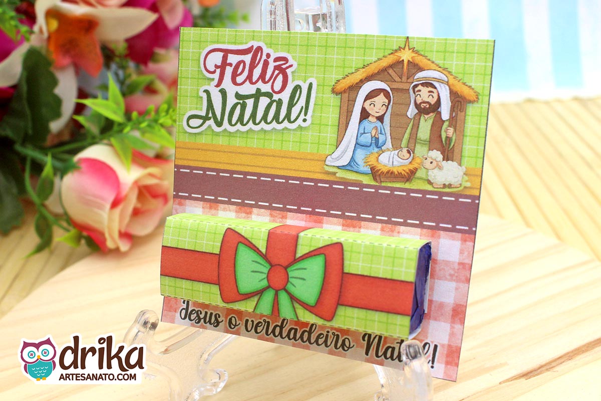 Porta-bis de Natal montado com a Sagrada Família e embalagem verde e vermelha do Bis em suporte transparente.