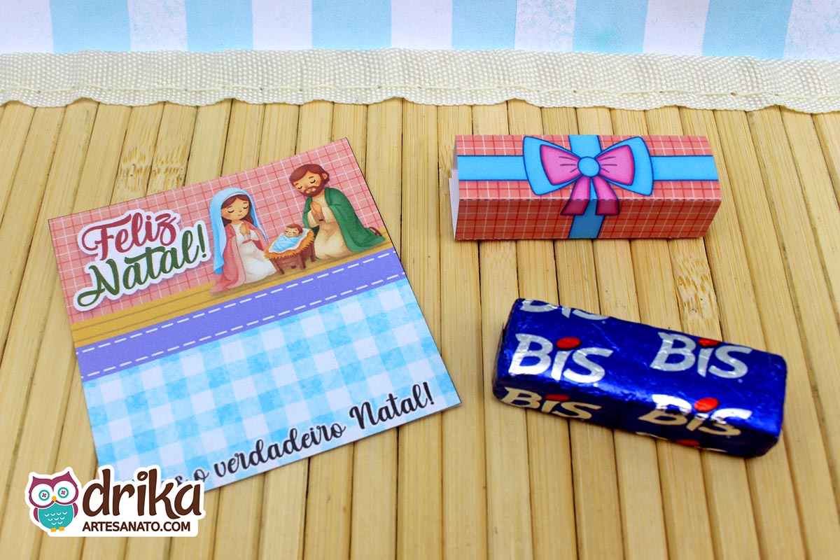 Cartão porta-bis de Natal com ilustração da Sagrada Família, rótulo de Bis simulando presente e chocolate Bis embalado, sobre fundo de bambu.