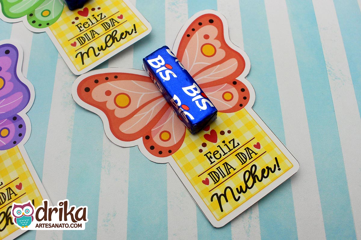 Vários cartões porta-bis de borboleta coloridos, um coral em destaque com chocolate Bis azul no centro