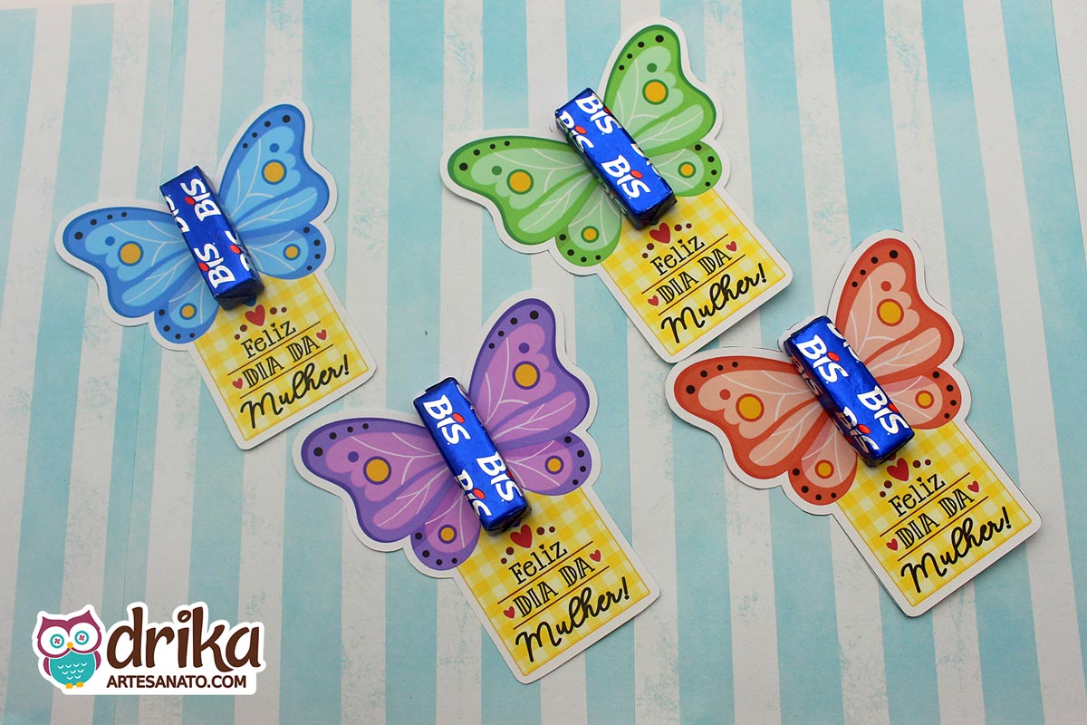 Quatro cartões porta-bis de borboleta coloridos (azul, verde, roxo, coral) com chocolates Bis azuis