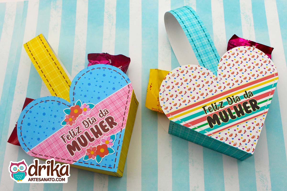 Duas cestinhas de coração de papel para o Dia da Mulher, uma azul com flores e outra com sapatinhos, recheadas com bombons