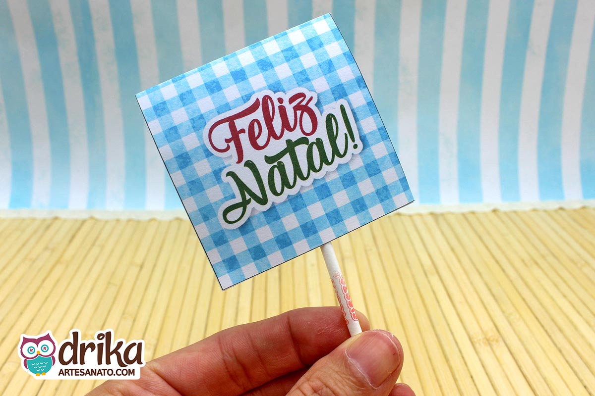 Verso da capinha para pirulito com estampa xadrez azul e mensagem "Feliz Natal!" em fonte cursiva