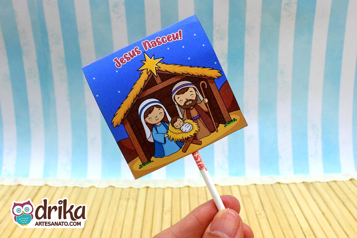 Capinha de pirulito com ilustração da Sagrada Família em presépio sob céu estrelado e frase "Jesus Nasceu"