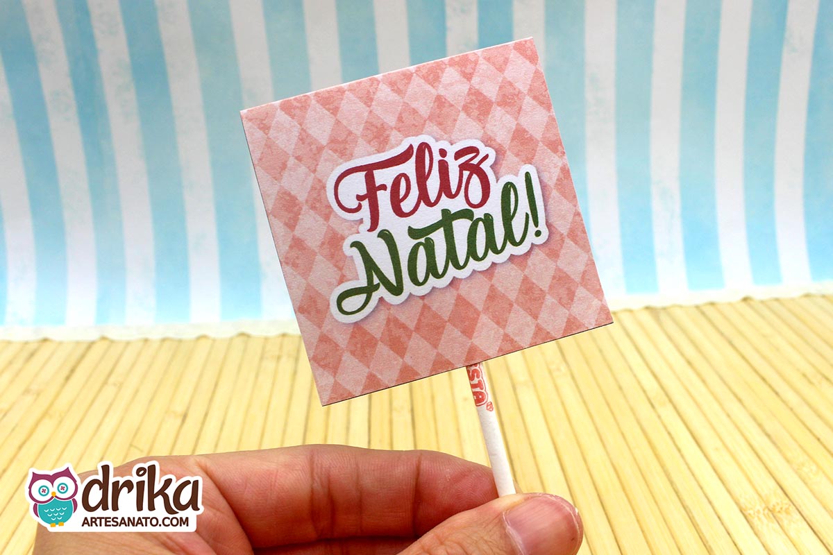Verso da capinha de pirulito com fundo xadrez rosa e mensagem "Feliz Natal" em letras verdes