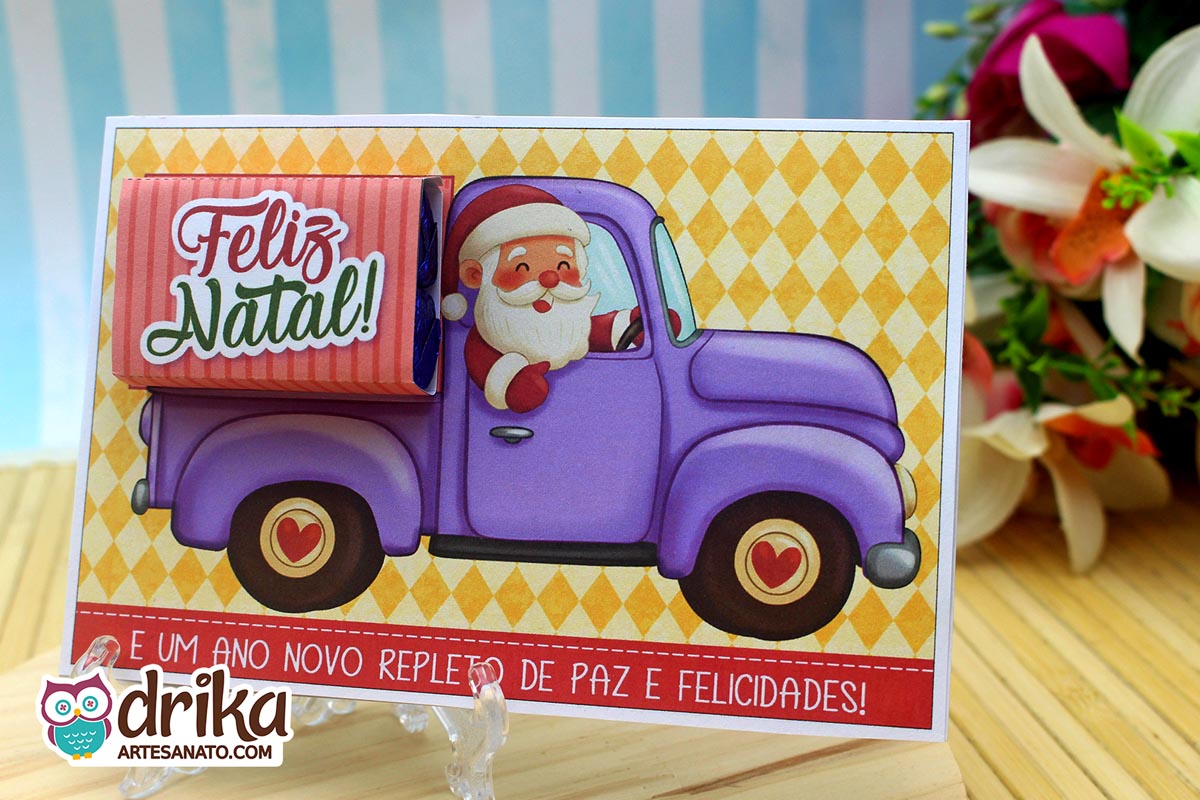 Cartão porta-bis de Papai Noel em caminhonete lilás, montado com cinta "Feliz Natal" e exibido em suporte