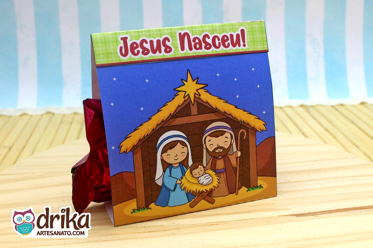 Porta-bombom de Natal com ilustração da Sagrada Família em frente a um estábulo sob céu estrelado e frase "Jesus Nasceu!"
