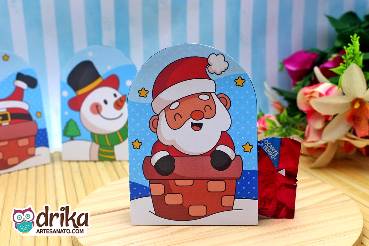 Porta-bombom de Papai Noel na chaminé com bombom vermelho ao lado, em base de madeira, com outros modelos desfocados