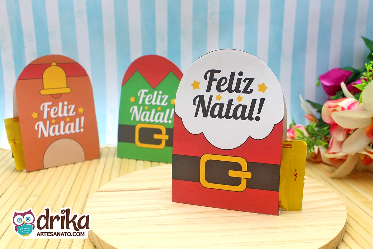Três porta-bombons de Natal: Papai Noel, sino dourado e chapéu de elfo, em base de madeira