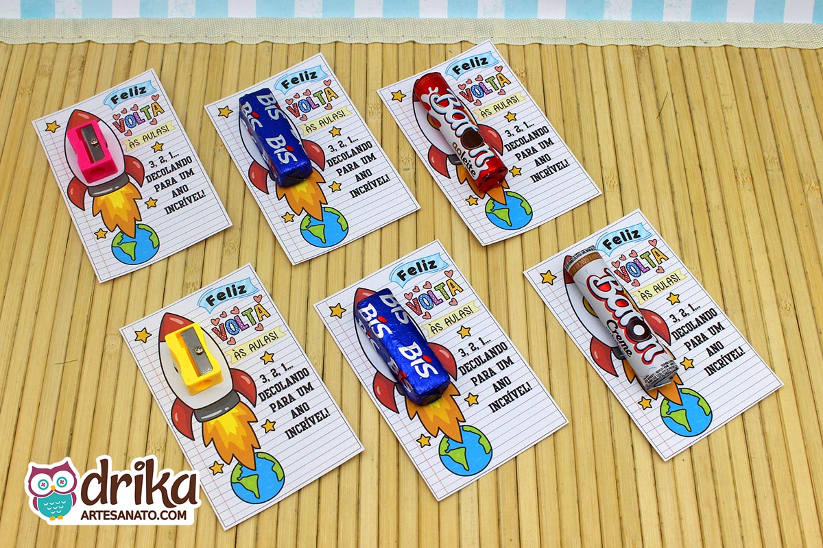 Seis cartões de Volta às Aulas com foguetes, dois com apontadores rosa, dois com amarelos e dois com chocolates Bis e Baton