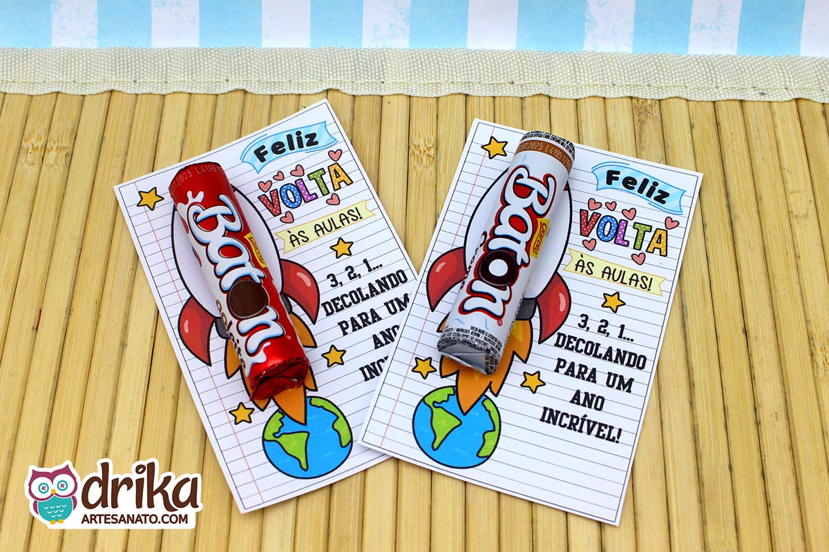 Dois cartões de foguete com chocolates Baton (um branco e um vermelho) lado a lado em uma mesa