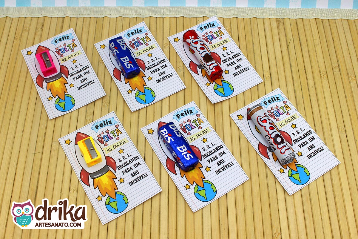 Seis cartões porta-bis com foguete, cada um com um mimo diferente como apontadores e chocolates, sobre um tapete de bambu
