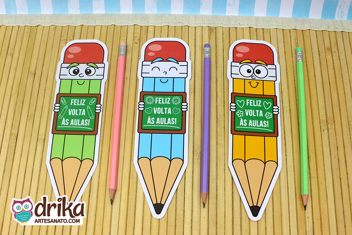 Três cartões porta-lápis gigantes de meninos, nas cores verde, azul e amarelo, com lápis de cor ao lado