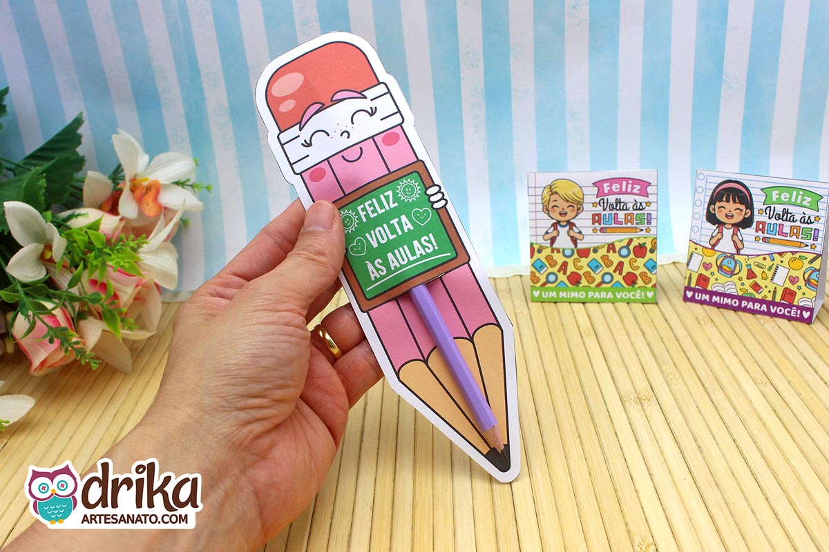 Mão segurando cartão porta-lápis gigante rosa com rostinho de menina e lápis roxo encaixado